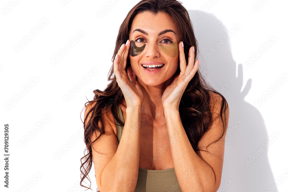 Fototapeta premium Beautiful smiling caucasian woman holding two colored patches under her eyes.