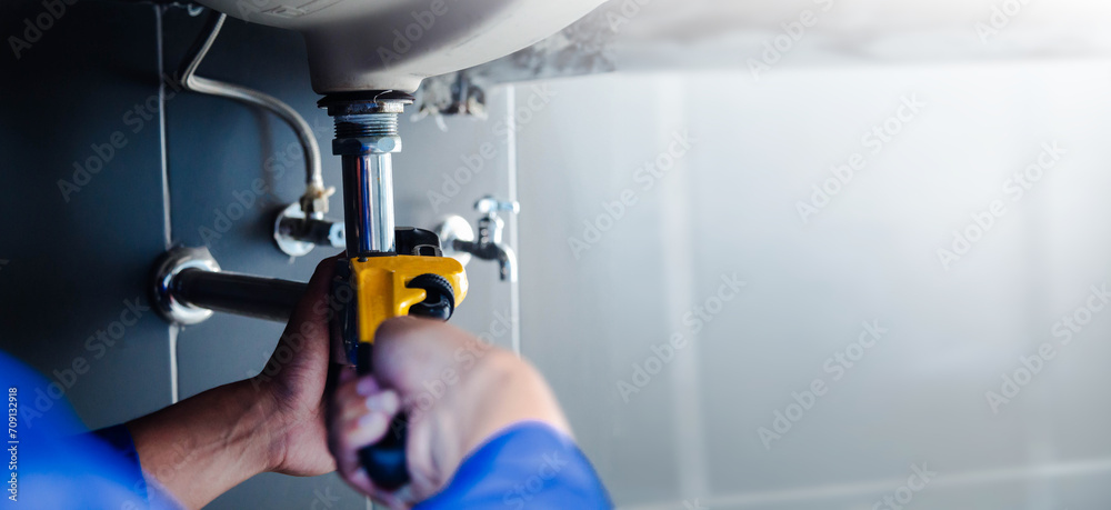 Plumber fixing white sink pipe with adjustable wrench. Plumber fixing white sink pipe with adjustable wrench.