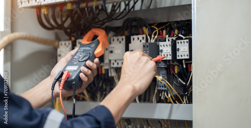 Electrician engineer work tester measuring voltage and current of power electric line in electical cabinet control   concept check the operation of the electrical system .