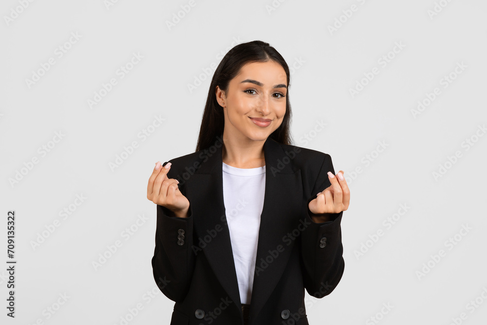 Happy european woman enjoy success in business, showing love sign with hands, gray studio background Happy european woman enjoy success in business, showing love sign with hands, gray studio background