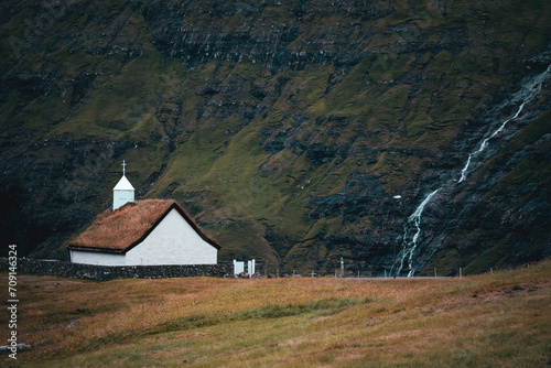 small white nordic church with a waterfall and mountains