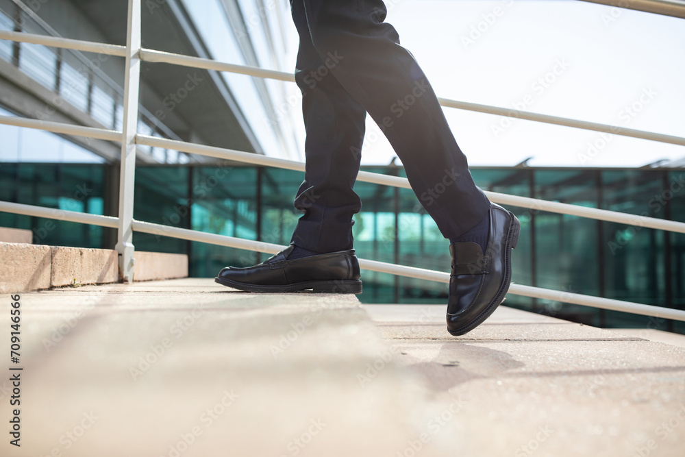 Cropped of male legs as unrecognizable businessman walking upstairs outside