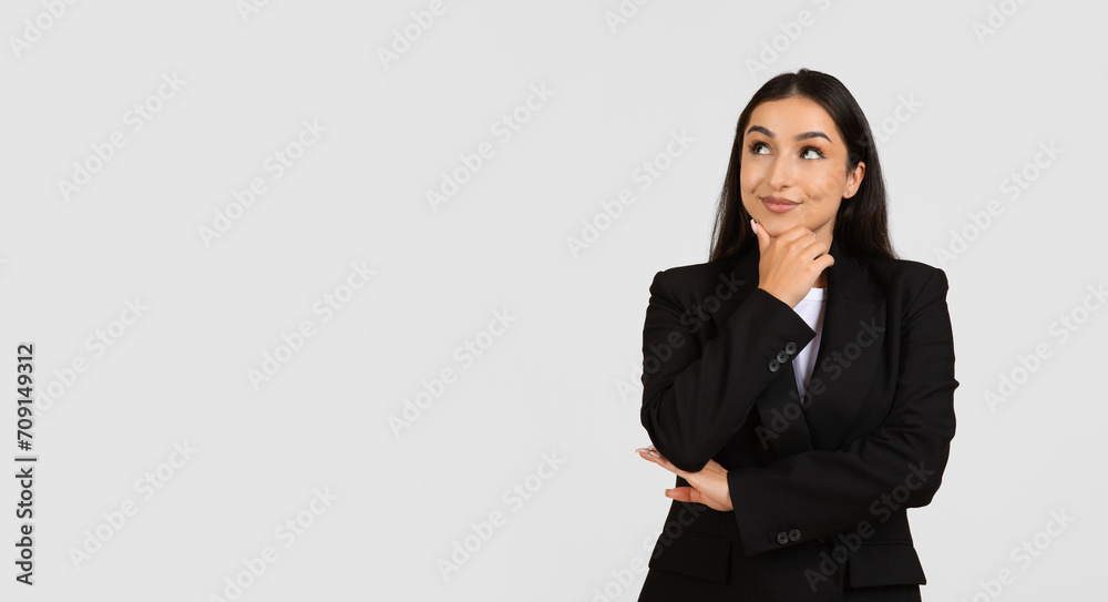 Cheerful pensive businesswoman in suit thinking, looking at empty space, isolated on gray background studio background Cheerful pensive businesswoman in suit thinking, looking at empty space, isolated on gray background studio background