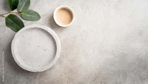 Top view of a concrete bowl and small cup on a textured concrete table with green leaves. Ideal for food display or culinary presentations  flatlay background.