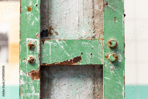Detail of a pillar with a green steel frame affected by rust in an old abandoned factory.