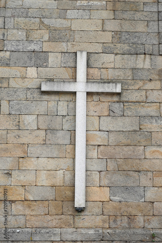 A large symbol of Christianity on a stone wall. This is a traditional cross.