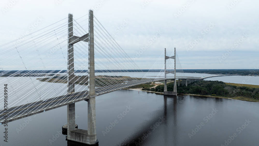 The Dames Point Bridge in Jacksonville, Florida, captured in daylight with cars driving over and water underneath.