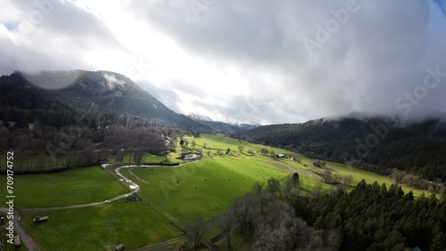 a scenic valley is shown under clouds in the valley, green fields, and trees