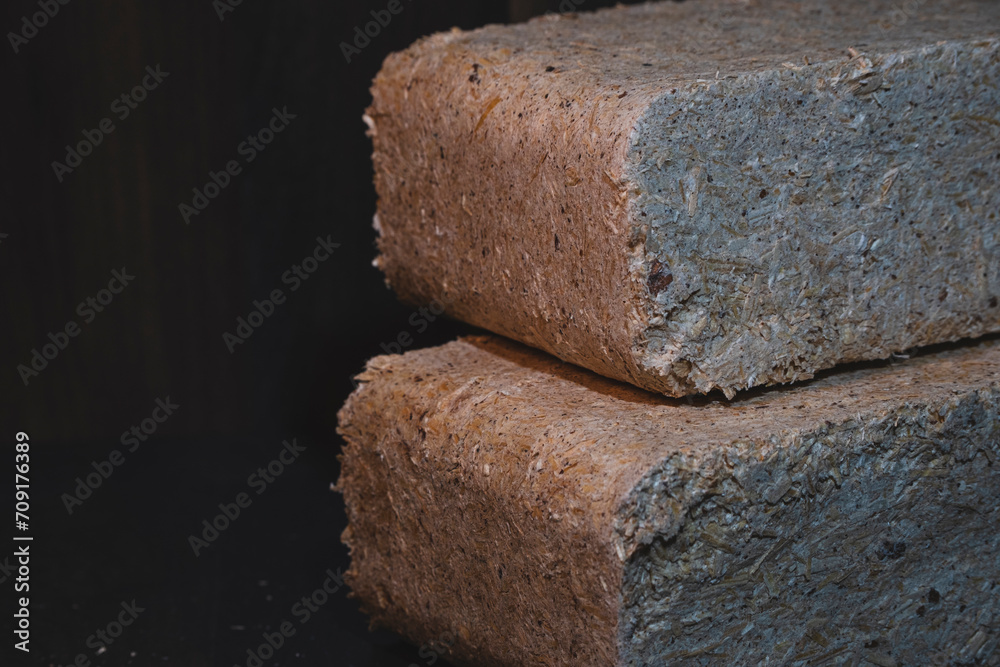 Close-up of a wood briquettes, pressed sawdust on a dark background. Solid fuel from wood chips and flax. Nature-friendly ecological fuel from renewable resources Close-up of a wood briquettes, pressed sawdust on a dark background. Solid fuel from wood chips and flax. Nature-friendly ecological fuel from renewable resources