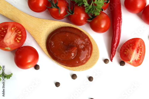 A wooden spoon with tomato sauce and vegetables lies on a white background.