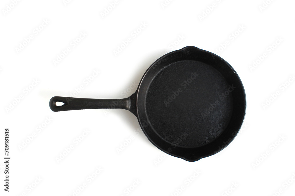 A black cast iron frying pan lies on a white background. A black cast iron frying pan lies on a white background.