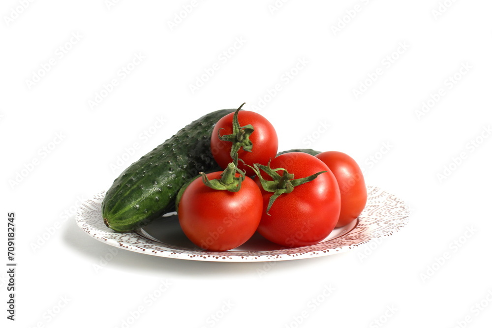 On a white background there is a plate with fresh vegetables, cucumbers and tomatoes. On a white background there is a plate with fresh vegetables, cucumbers and tomatoes.