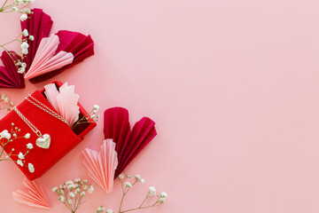 Happy Valentine's day ! Stylish pink and red hearts, flowers and heart necklace flat lay on pink background. Valentines hearts paper cutouts and jewelry gift. Love and mother's day