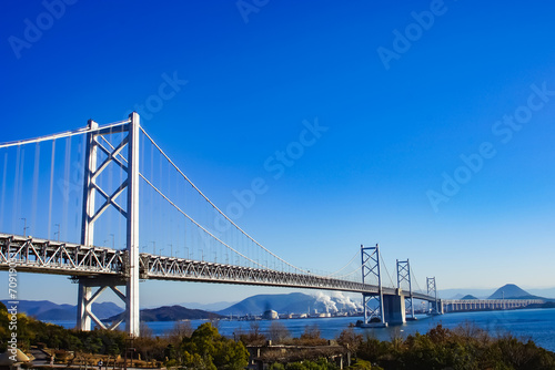 The Seto Ohashi Bridge spans the calm Seto Inland Sea in Japan under a clear blue sky, connecting Okayama and Kagawa with a dual car and train route. photo