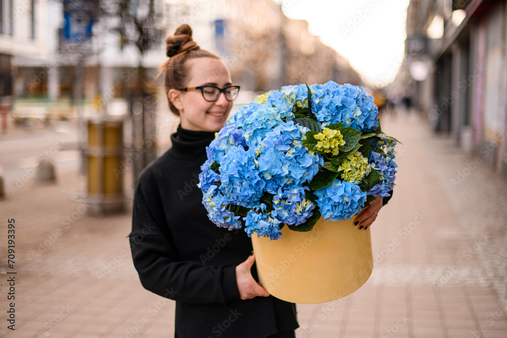 Fototapeta premium Gift box with beautiful luxury bouquet of blue hydrangeas in woman florist hands.