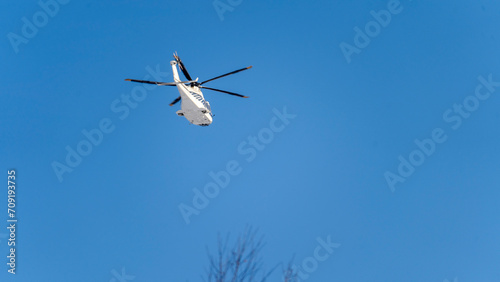 White helicopter on blue sky background, Close-up, selective focus, tinted image. Helicopter flight, delivery of passengers by air