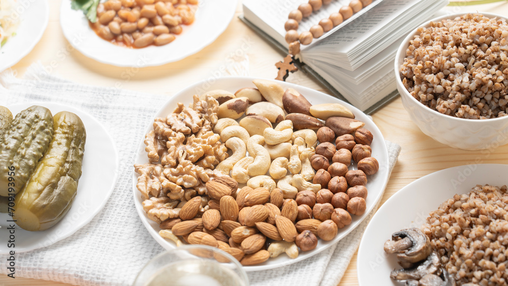 Lenten food in Lent on wooden background, nuts on plate, cashews, hazelnuts, almonds, walnuts