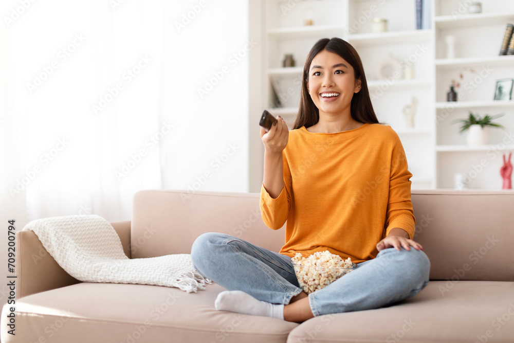 Happy young chinese lady enjoying time at home, watching TV Happy young chinese lady enjoying time at home, watching TV
