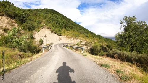 French way through Aragon - shadow of a touring cyclist riding a paved road after Puente la Reina de Jaca, province of Huesca, La Jacetania, Aragon, Spain photo