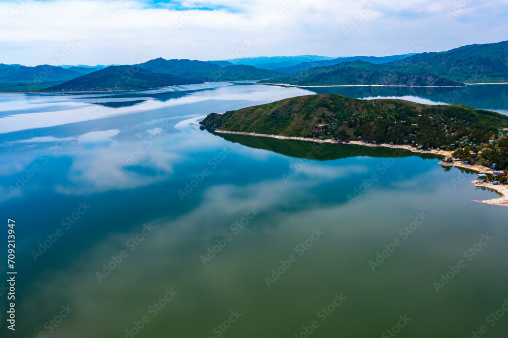 Top view of the turquoise water of a mountain lake. Clean clear water with streaks on the bottom. Patterns from a mountain river. The color shimmers from blue-green to blue. Trees in the water. Issyk