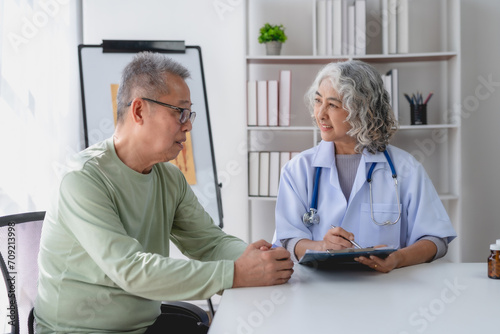 Senior Asian female doctor talking and counseling with an elderly male patient.