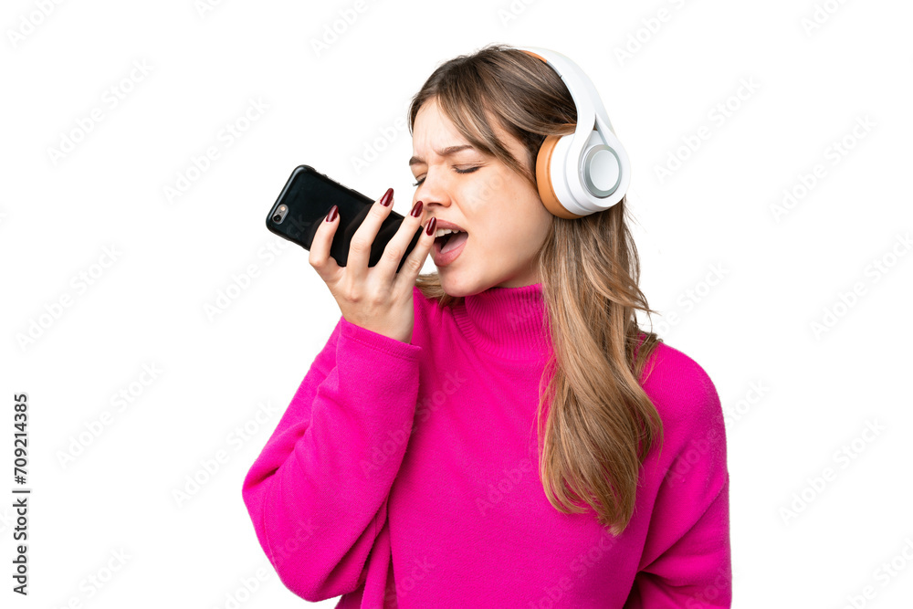 Obraz premium Young girl over isolated chroma key background listening music with a mobile and singing