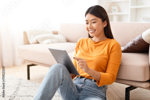 Happy asian woman reading news on digital tablet, home interior Free Download Happy asian woman reading news on digital tablet, home interior - GFXLoad