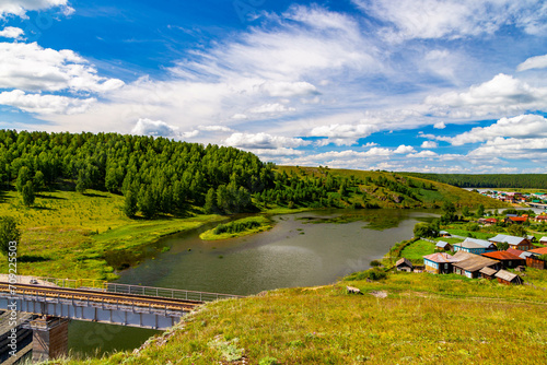 River with suspension bridge at old Urals village, Russia. © vladimircaribb