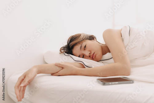 Sad and depressed Asian woman lie awake in the morning to weak to get up form bed.