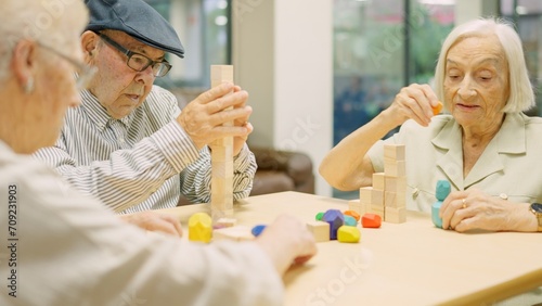 Concentrated seniors resolving brain skill games with pieces in geriatric photo