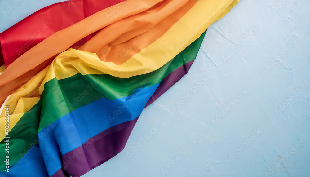 Top view of rainbow flag on a blue background with copy space