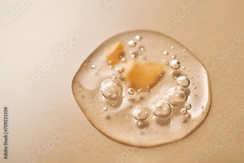 A drop of transparent cosmetic gel on a beige background.