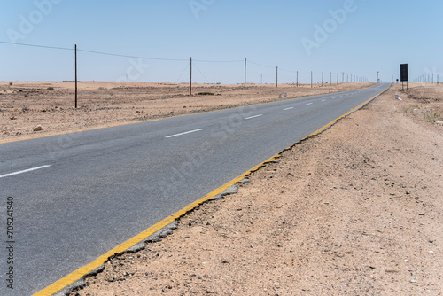 electricity posts and tar road in desert countryside, near Usakos,  Namibia photo