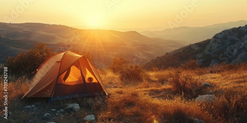 Golden Hour Camping: Tent Illuminated by Sunset in Rugged Terrain photo