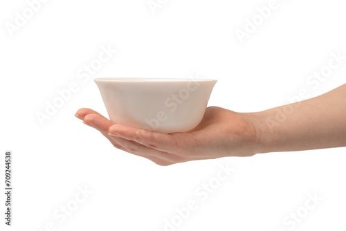 Female hand is holding a ceramic bowl isolated on white background. photo
