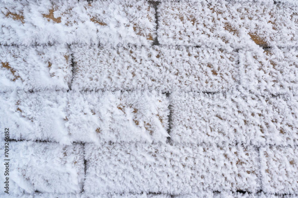Close-up of a brick wall covered with large flakes of frost. Background Close-up of a brick wall covered with large flakes of frost. Background