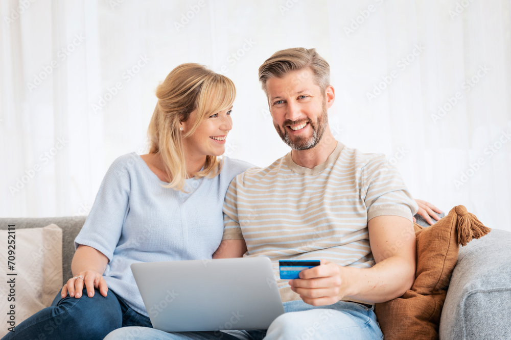 Mature couple sitting at home and using laptop for shopping online
