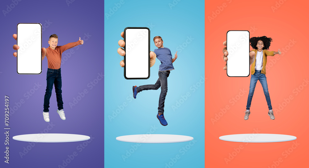 Happy Children Jumping With Big Blank Smartphone In Hands, Showing Thumbs Up Happy Children Jumping With Big Blank Smartphone In Hands, Showing Thumbs Up