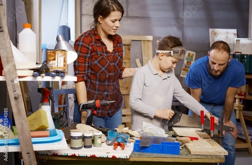 Diy family tinkering in workshop, little boy using saw.