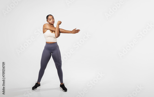 Full length of black fitness woman stretching arms training, studio