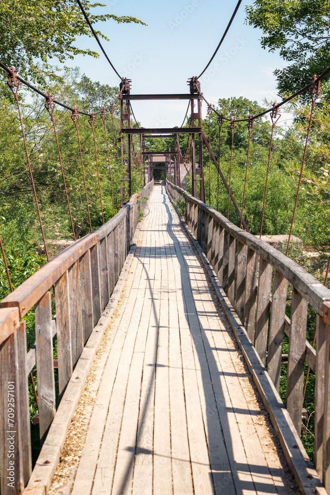 A long suspension pedestrian bridge with rusted metal structures in Lithuania.