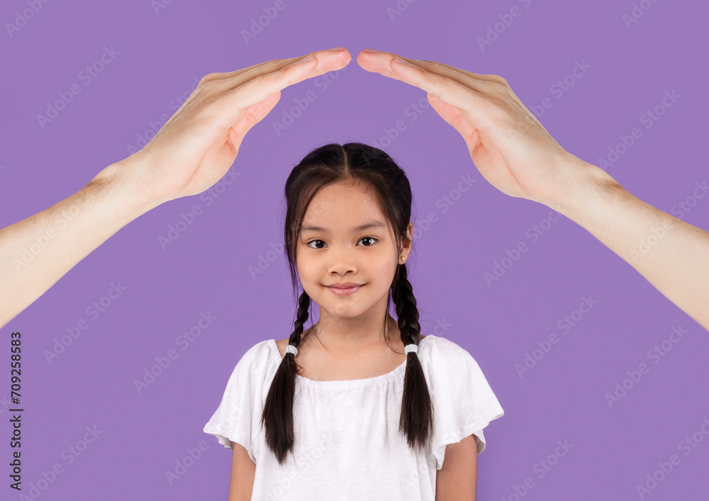 Happy school aged asian girl under hands roof Happy school aged asian girl under hands roof