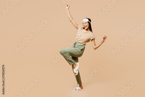 Full body happy excited overjoyed young calm Latin woman wears pyjamas jam sleep eye mask rest relax at home do winner gesture isolated on plain pastel beige background. Good mood night nap concept. © ViDi Studio