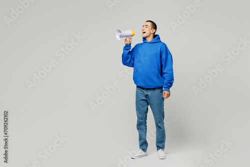 Full body young middle eastern man he wear blue hoody casual clothes hold in hand megaphone scream announces discounts sale Hurry up isolated on plain solid white background studio. Lifestyle concept.