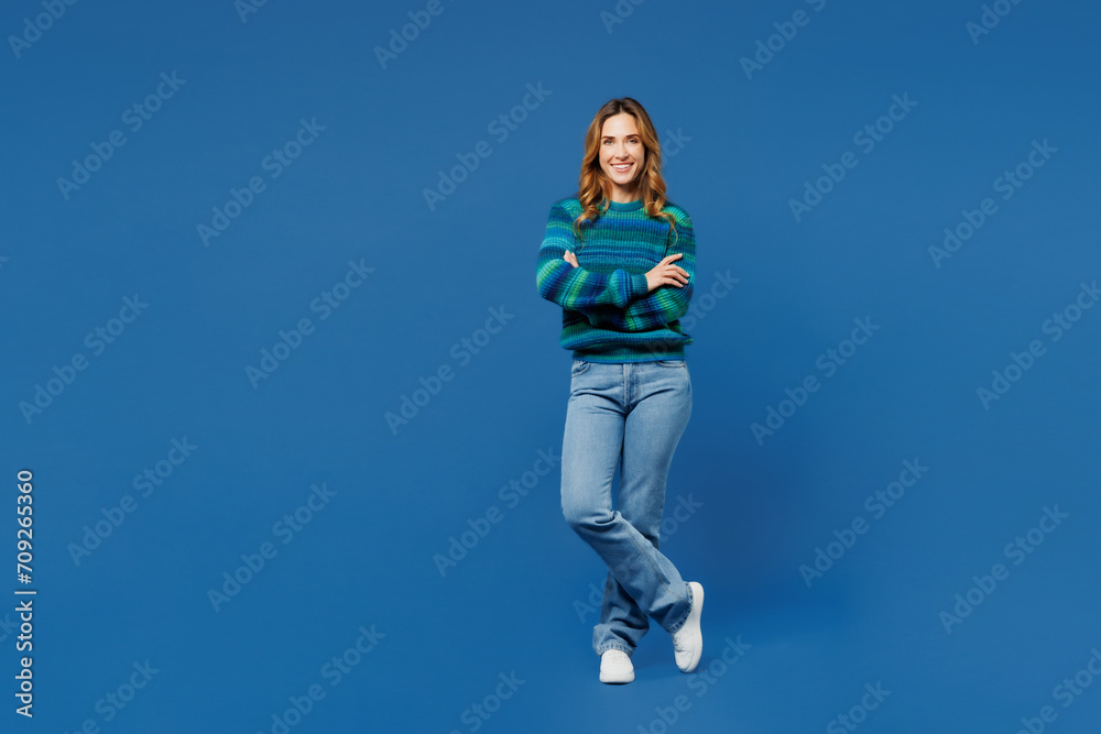Full body smiling happy fun young woman she wears knitted sweater casual clothes hold hands crossed folded look camera isolated on plain blue cyan color background studio portrait. Lifestyle concept. Full body smiling happy fun young woman she wears knitted sweater casual clothes hold hands crossed folded look camera isolated on plain blue cyan color background studio portrait. Lifestyle concept.