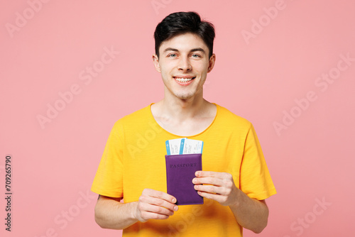 Traveler man wear yellow casual clothes hold boarding passport ticket isolated on plain pastel pink background. Tourist travel abroad in free spare time rest getaway. Air flight trip journey concept. #709265790