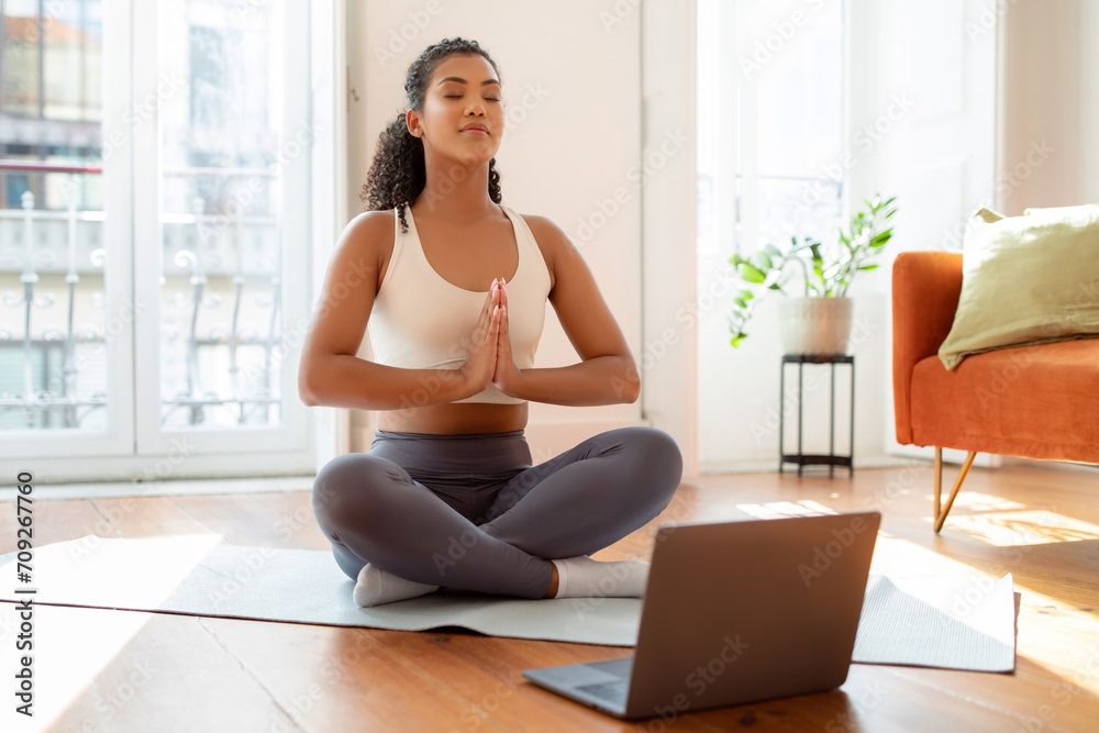 lady practicing yoga and meditation in front of laptop indoors lady practicing yoga and meditation in front of laptop indoors