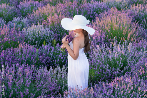 Teen girl with lavender flower standing in the field. teen girl with lavender holding a flower bouquet. Teen girl in a dress walking in lavender park. teen girl with lavender in field