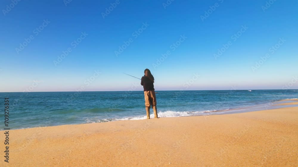 Woman fishing on the shoreline on a beautiful and peaceful beach Woman fishing on the shoreline on a beautiful and peaceful beach