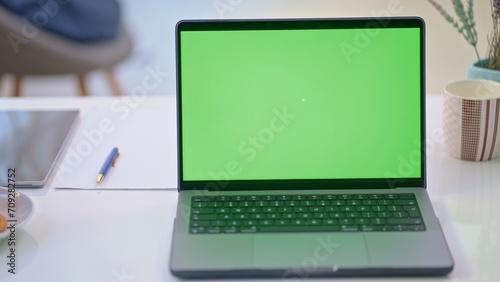 Laptop computer on desk with blank chromakey green screen. Home office, working from home, website application or webshop, for selling product online.